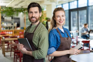 Pizzacı. Pizzacıda mutlu ve kendinden emin iki garson müşterileri bekliyor.