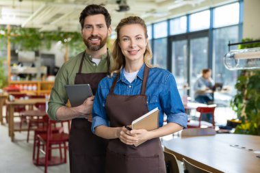 Pizzacı. Pizzacıda mutlu ve kendinden emin iki garson müşterileri bekliyor.