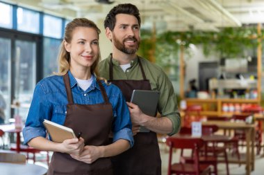 Pizzacı. Pizzacıda mutlu ve kendinden emin iki garson müşterileri bekliyor.