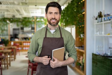 Müşterileri bekliyorum. Önlüklü genç sakallı adam pizzacıda müşterisini beklerken kendinden emin görünüyor.