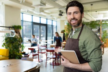 Müşterileri bekliyorum. Önlüklü genç sakallı adam pizzacıda müşterisini beklerken kendinden emin görünüyor.