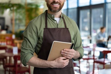 Müşterileri bekliyorum. Önlüklü genç sakallı adam pizzacıda müşterisini beklerken kendinden emin görünüyor.