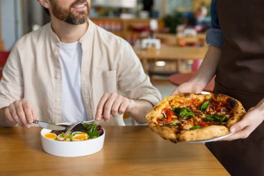 Lezzetli pizza. Müşteri pizzasını pizzacıdan alıyor ve memnun görünüyor.