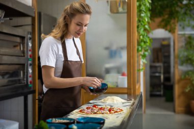 Mutfakta pizza hazırlayan kadın evde yemek yapıyor.