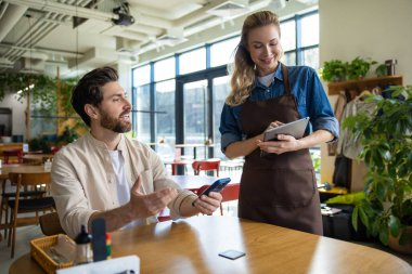 Garson restoranda tabletle sipariş veriyor. Adam içeride telefonla konuşurken dikkatli yazıyor.