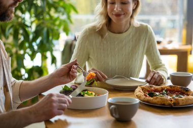 Restoranda salata ve pizza yiyen insanlar yemeklerini evde yemekten zevk alıyorlar.