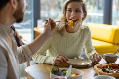 Restoranda salata ve pizza yiyen insanlar yemeklerini evde yemekten zevk alıyorlar.