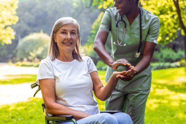 Bakıcı ve yaşlılar altın güneş ışığıyla parkta rehabilitasyon egzersizi yapıyorlar.