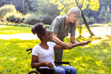 Bakıcı ile parkta rehabilitasyon gören yaşlı kişi