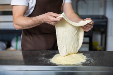 Pizza için Hamur. Pizza için hamur işiyle uğraşan fırıncının resmini kapat.