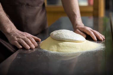 Hamurla çalışmak. Pizza hazırlamak için hamuru yoğuran adamların ellerini kapat.