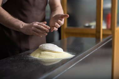 Hamurla çalışmak. Pizza hazırlamak için hamuru yoğuran adamların ellerini kapat.