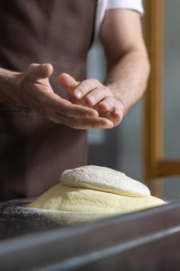 Hamurla çalışmak. Pizza hazırlamak için hamuru yoğuran adamların ellerini kapat.