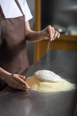 Pizza pişiriyorum. Pizzayı hazırlarken hamura un döken kadınların ellerini kapat.