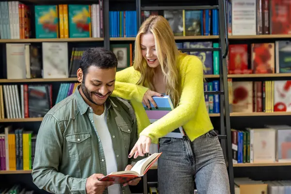 Kütüphanede. Uzun saçlı sarışın kadın ve kütüphanedeki koyu saçlı adam.