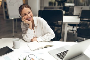 İş kadını dizüstü bilgisayarla çalışıyor. Modern ofis ortamında, akşamları.