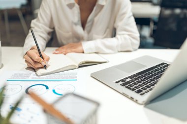 İş kadını not defterinde beyaz tahtayla birlikte çağdaş ofis ayarlarında görünür notlar alıyor