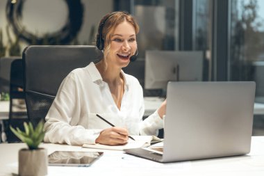 Gece çağdaş ofis alanında müşteri hizmetleri için dizüstü bilgisayar kullanan kadın