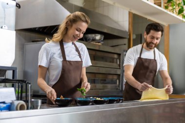 Erkek hamuru yuvarlıyor, kadınla mutfakta çalışıyor. Kapalı alanda yemek hazırlıyor.