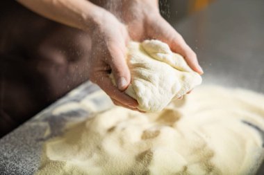 Mangırı yuvarlayan kişi mutfağı düzleştirir pizzayı içeride dikkatlice hazırlar.