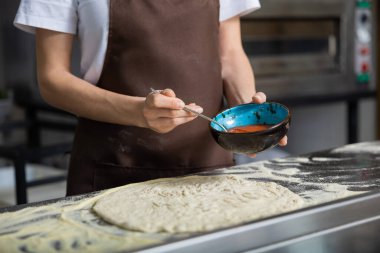 Kadın soslu pizza mutfağını dağıtıyor yemek hazırlıyor içeride eğleniyor.