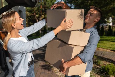 Yeni bir eve taşınıyorum. Yeni bir eve taşınırken arabaya kutu taşıyan genç bir çift.