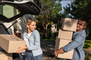 Yeni bir eve taşınıyorum. Yeni bir eve taşınırken arabaya kutu taşıyan genç bir çift.