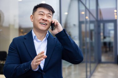 İletişim. Elinde telefon olan takım elbiseli genç Asyalı adam.