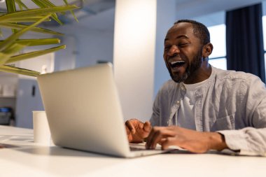 Çalışıyorum. İş yerinde dizüstü bilgisayarın başında Afro-Amerikalı bir adam var.