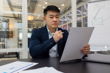 Meşgulüm. Genç Asyalı yönetici yeni bir proje üzerinde çalışıyor ve meşgul görünüyor.