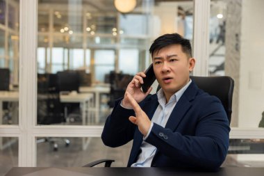 Telefon var. Asyalı genç müdürün telefonu var. Meşgul ve ilgili görünüyor.