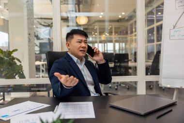 Telefon var. Asyalı genç müdürün telefonu var. Meşgul ve ilgili görünüyor.