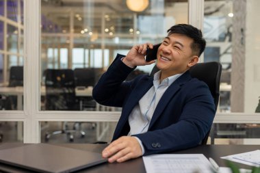 Telefon var. Asyalı genç müdürün telefonu var. Meşgul ve ilgili görünüyor.