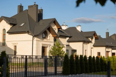 Güneşli bir günde, çitleri ve yeşilliği olan modern meskenler.