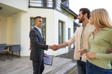 Ev satın alımını kutlayan çiftler yeşil alanda güneş ışığı altında