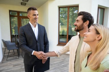 Ev satın alımını kutlayan çiftler yeşil alanda güneş ışığı altında