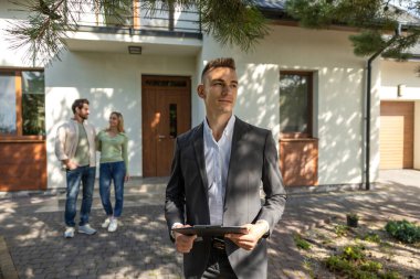 Modern evin dışında panosu olan çiftli bir emlakçı.