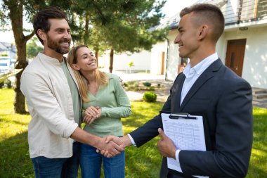 Ev satın alımını kutlayan çiftler yeşil alanda güneş ışığı altında