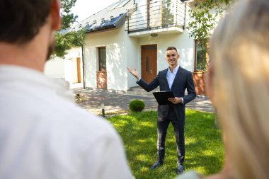 Ajans, açık gökyüzü olan banliyö bahçesindeki müşterilere yeni evi gösteriyor