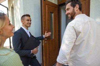 Menajer müşterilerini temiz gökyüzü ile banliyö ortamında yeni bir eve davet ediyor.