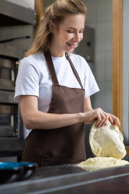 Gülümseyen kadın fırıncı neşeli bir fırında bir kase hamur tutuyor, hazırlanmaya hazır.