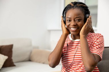 İnternette. Gülümseyen ve mutlu genç Afro-Amerikalı kadın internette bir şeyler dinliyor.