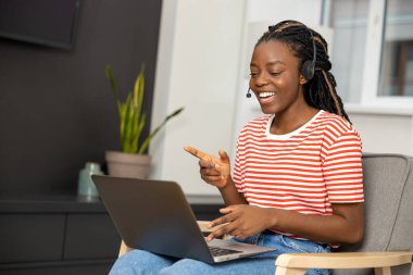 Evden çalışıyorum. Bilgisayarlı, gülümseyen güzel bir kadın. Mutlu görünüyor.