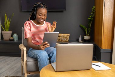 İnternette. Kulaklıklı, dizüstü bilgisayarı olan Afrikalı Amerikalı genç bir kadın.