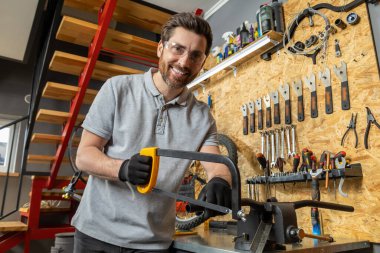 Profesyonel kıyafetli sakallı bir velomekanik. Atölye ayarlarında özel aletleri olan bisiklet tamircisi.