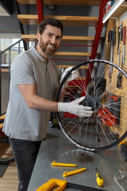 Bisiklet tamirciliği yapan yetenekli bir tamirci iyi organize edilmiş atölyede bisiklet tamirciliği yapıyor.