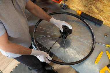 Bisiklet tamirciliği yapan yetenekli bir tamirci iyi organize edilmiş atölyede bisiklet tamirciliği yapıyor.