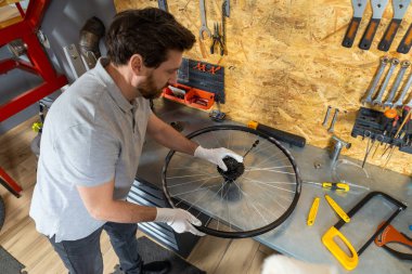 Bisiklet tamirciliği yapan yetenekli bir tamirci iyi organize edilmiş atölyede bisiklet tamirciliği yapıyor.