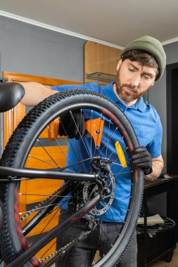 Sakallı tamirci modern atölyede bisiklet lastiğini tamir ediyor.