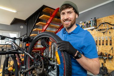 Sakallı tamirci modern atölyede bisiklet lastiğini tamir ediyor.